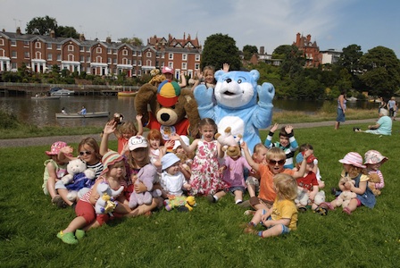 Kids, Parents, and museum Mascot posing at a picnic.